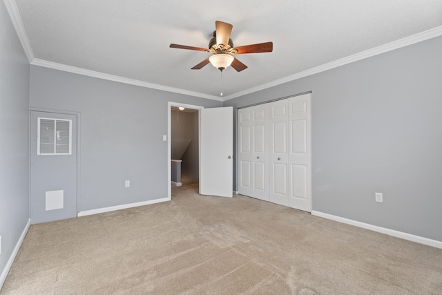 unfurnished bedroom with a closet, baseboards, carpet floors, and crown molding