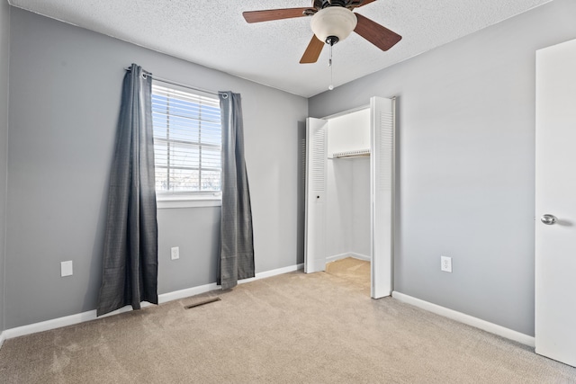 unfurnished bedroom featuring visible vents, carpet floors, a textured ceiling, and baseboards