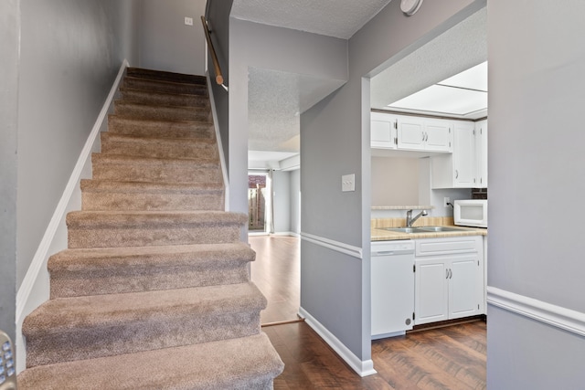 stairway with wood finished floors, baseboards, and a textured ceiling