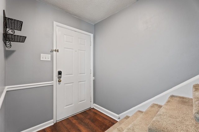 foyer with dark wood finished floors, stairway, baseboards, and a textured ceiling