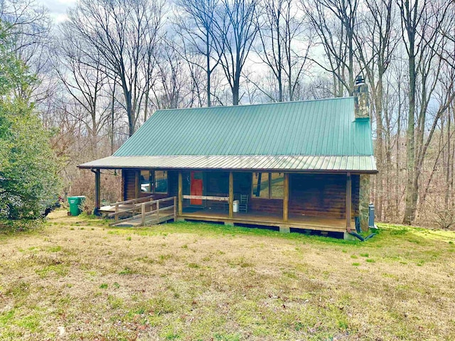 chalet / cabin featuring log siding, metal roof, covered porch, and a chimney