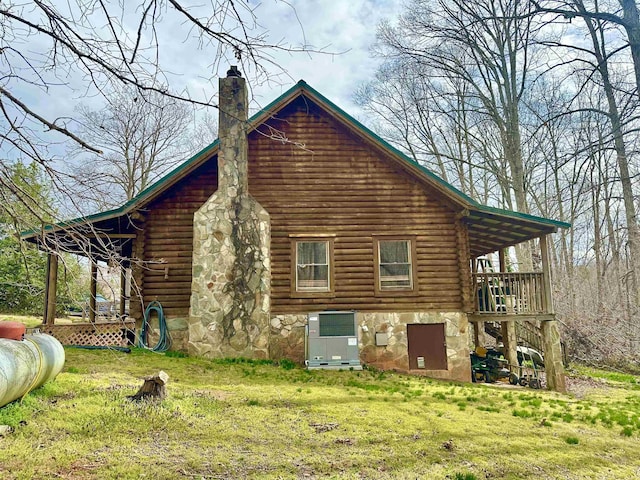 view of side of home with a yard, log exterior, and a chimney