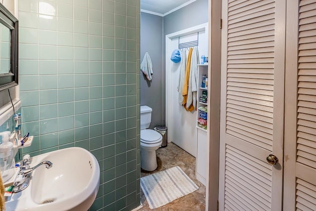 bathroom featuring a sink, crown molding, a closet, tile walls, and toilet