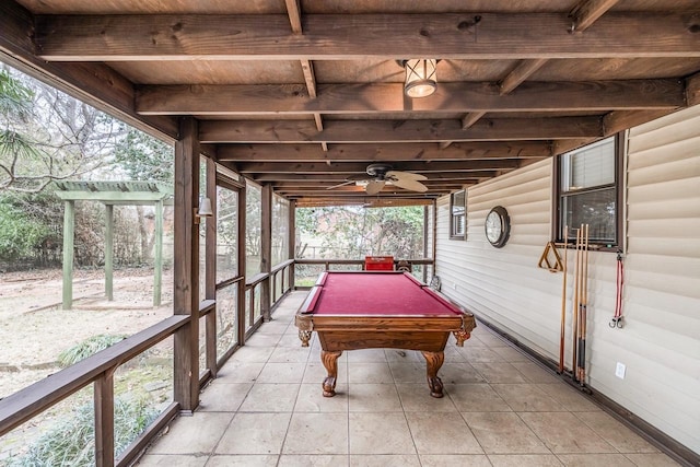 recreation room featuring ceiling fan, wooden ceiling, beamed ceiling, and rustic walls