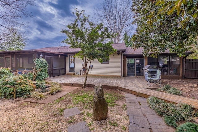 back of house with a wooden deck, roof with shingles, and a sunroom