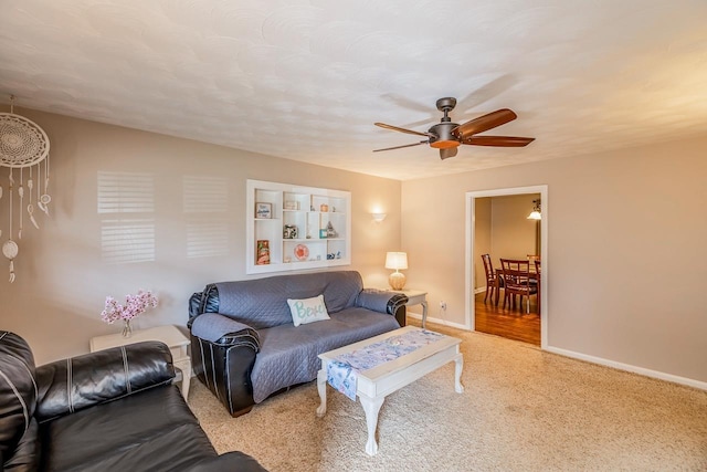 living area with a ceiling fan, baseboards, and carpet floors