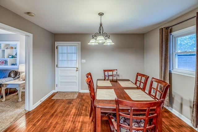 dining space with a chandelier, baseboards, and wood finished floors