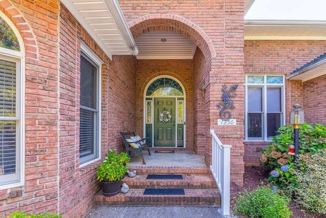 view of exterior entry featuring brick siding and a porch