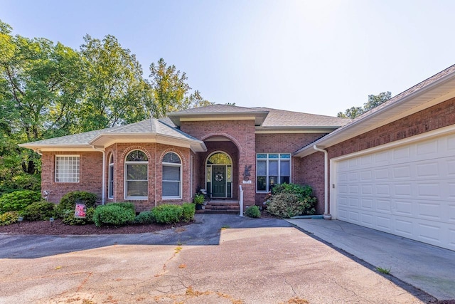 single story home with brick siding, concrete driveway, and a shingled roof