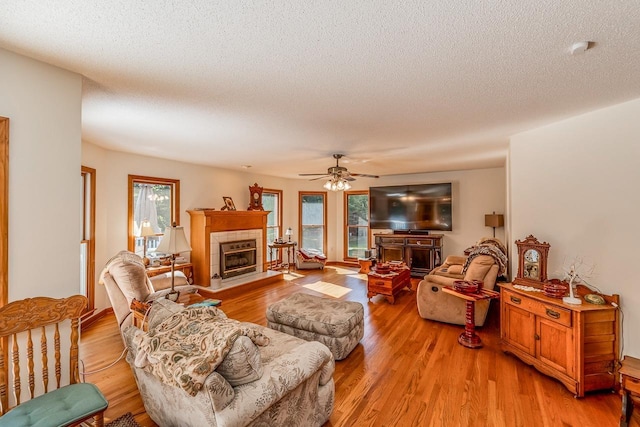 living area featuring a fireplace, a textured ceiling, and light wood-type flooring