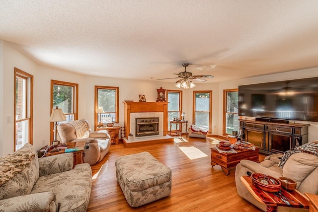 living area with a textured ceiling, light wood-style flooring, and a tile fireplace