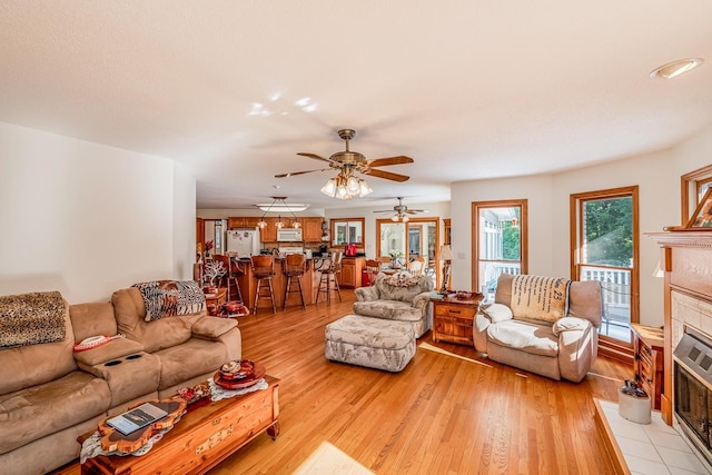 living room with a tiled fireplace and light wood finished floors