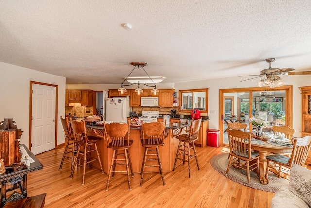 dining space with light wood-type flooring and a textured ceiling