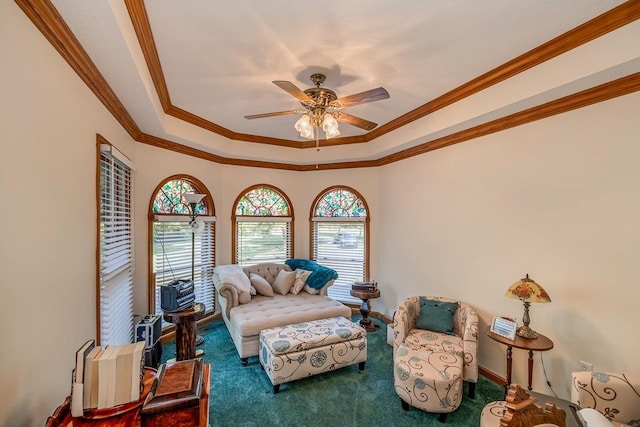 carpeted living room with a tray ceiling, crown molding, and a ceiling fan