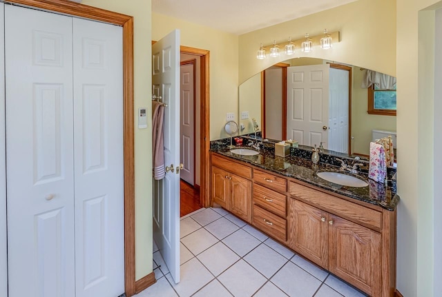 bathroom featuring a sink, a closet, double vanity, and tile patterned flooring