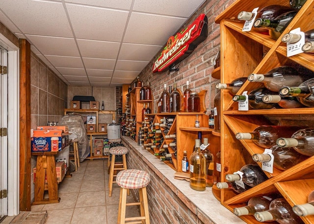 wine cellar featuring a drop ceiling, brick wall, and tile patterned flooring