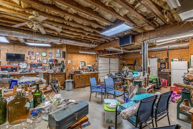 garage with a workshop area, a ceiling fan, and freestanding refrigerator