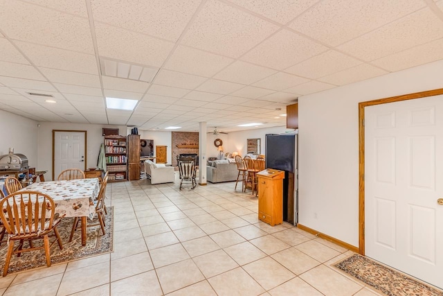 dining room with visible vents, a drop ceiling, a fireplace, light tile patterned floors, and baseboards