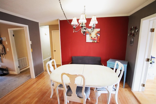 dining space featuring visible vents, ornamental molding, light wood-style floors, baseboards, and a chandelier