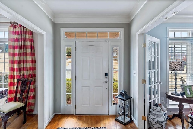 foyer entrance featuring a healthy amount of sunlight, wood finished floors, and crown molding