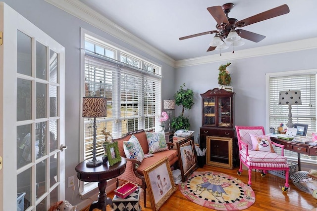 living area with crown molding, a ceiling fan, and wood finished floors