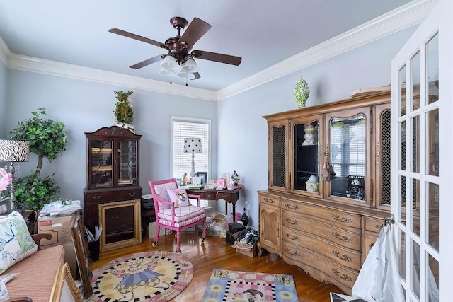 living area with crown molding, a ceiling fan, and wood finished floors