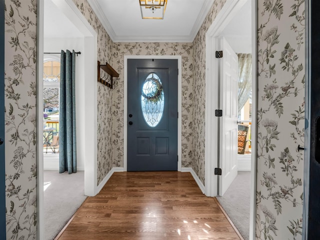 carpeted entryway with wallpapered walls, wood finished floors, and ornamental molding