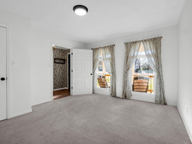 unfurnished bedroom with carpet flooring, baseboards, and a textured ceiling