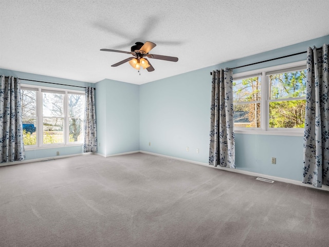 unfurnished room featuring visible vents, carpet flooring, a textured ceiling, and baseboards