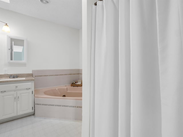 bathroom with tile patterned floors, a textured ceiling, a bath, and vanity