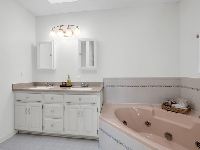 bathroom with double vanity, a tub with jets, tile patterned floors, and a sink