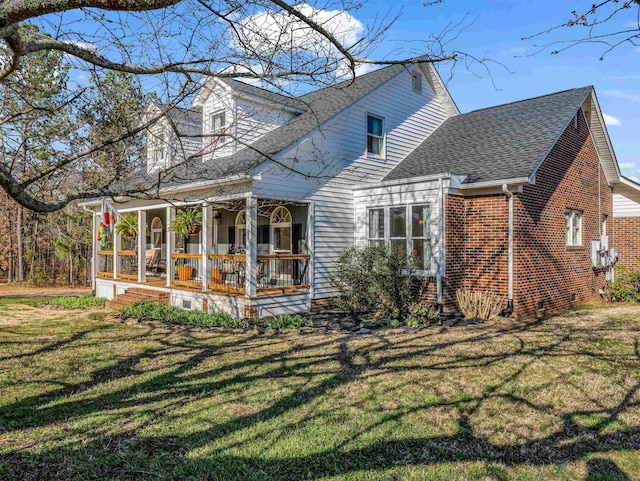 rear view of property featuring a lawn, a porch, brick siding, and a shingled roof