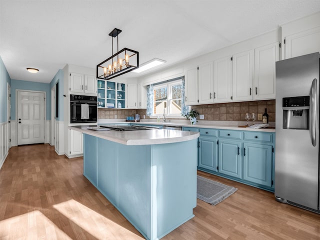 kitchen with light wood finished floors, blue cabinetry, oven, light countertops, and stainless steel refrigerator with ice dispenser