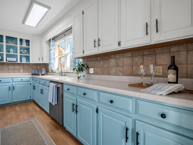 kitchen with light wood-style flooring, a sink, light countertops, stainless steel dishwasher, and blue cabinets