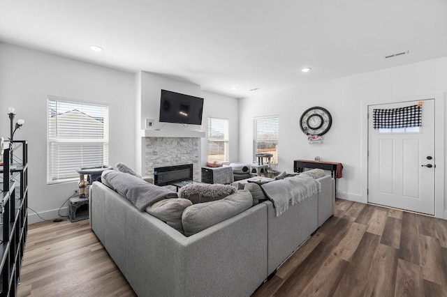 living room featuring visible vents, baseboards, recessed lighting, a fireplace, and wood finished floors