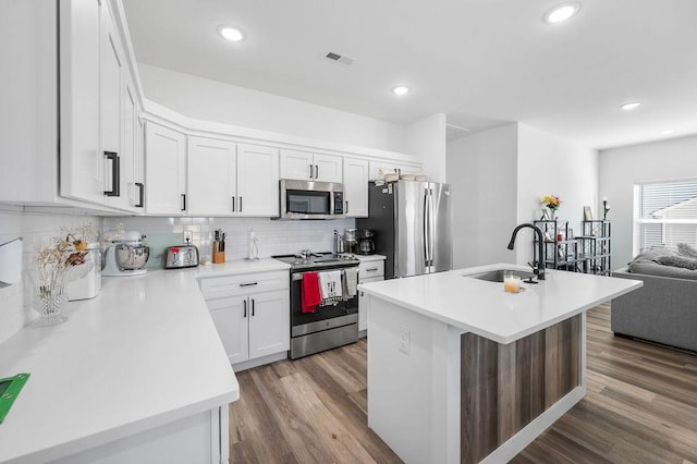 kitchen with a sink, stainless steel appliances, visible vents, and wood finished floors