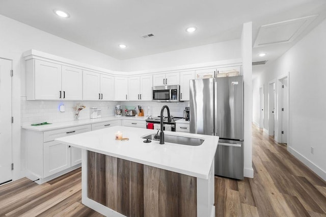 kitchen with stainless steel appliances, visible vents, wood finished floors, and white cabinets