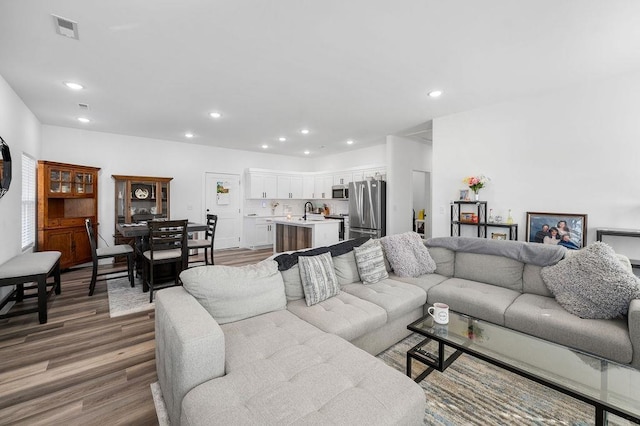 living room with visible vents, recessed lighting, and wood finished floors