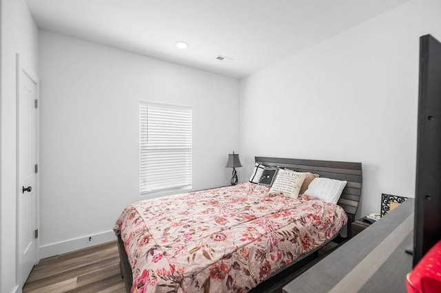 bedroom with visible vents, baseboards, and wood finished floors