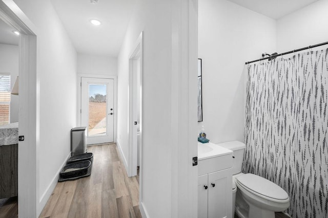 bathroom featuring toilet, wood finished floors, a shower with shower curtain, baseboards, and vanity