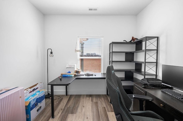 home office with visible vents, wood finished floors, and radiator heating unit