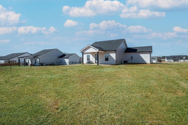 back of property featuring central AC unit, a residential view, a lawn, and fence