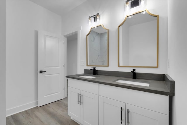 full bathroom featuring double vanity, wood finished floors, baseboards, and a sink