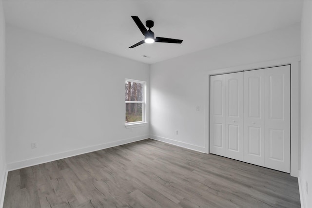 unfurnished bedroom with a closet, ceiling fan, baseboards, and wood finished floors