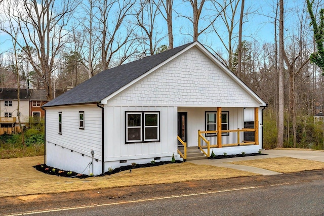 modern farmhouse style home featuring a porch, board and batten siding, a front yard, a shingled roof, and crawl space