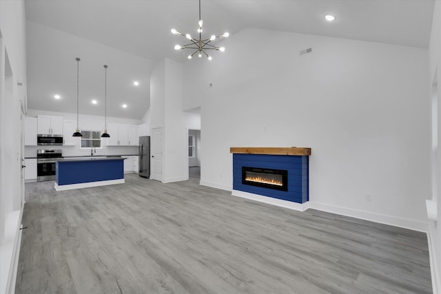 unfurnished living room featuring visible vents, baseboards, light wood-style floors, a glass covered fireplace, and a chandelier