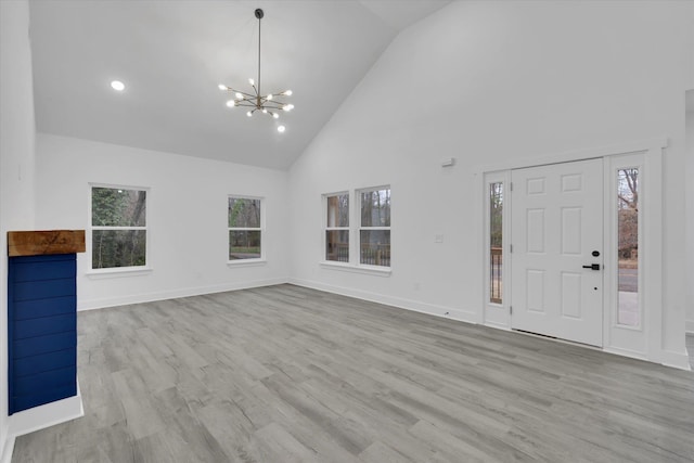 foyer with baseboards, wood finished floors, high vaulted ceiling, and a chandelier