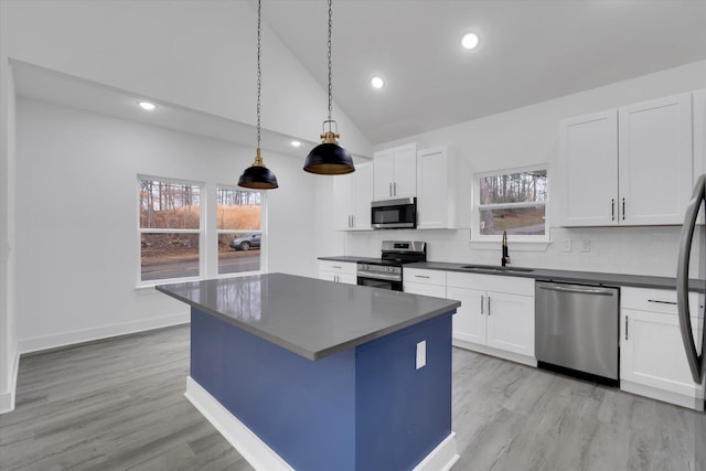 kitchen with dark countertops, a center island, decorative backsplash, stainless steel appliances, and a sink