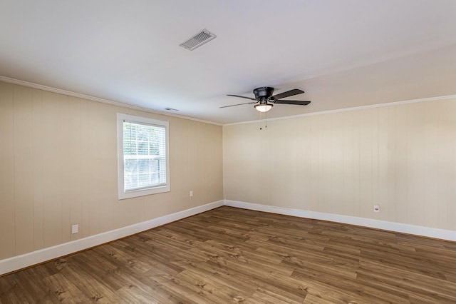 spare room with wood finished floors, baseboards, visible vents, ceiling fan, and ornamental molding