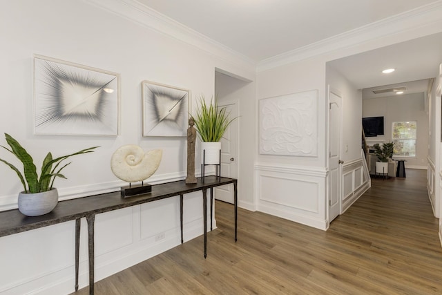 hallway with a decorative wall, ornamental molding, and wood finished floors